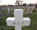 A white cross in a graveyard showing the letters RIP