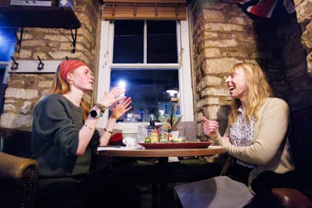 Matilda and Tamsin sitting at a restaurant table chatting and laughing