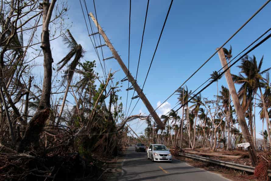 Cars drive under a partially collapsed utility pole after the island was hit by Hurricane Maria.