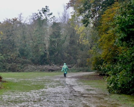 Person in a light green raincoat walking through a muddy parkland