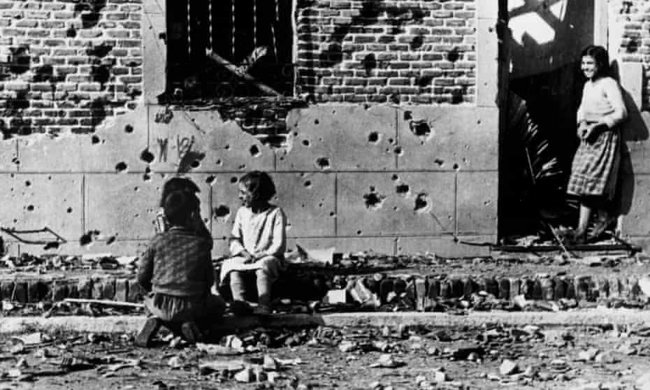 Children, unaware of the horror of war, play in front of the shrapnel-hit facade of No 10 Peironcely street, Madrid. November-December 1936.