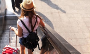 Tourist girl with suitcase down the escalator.
