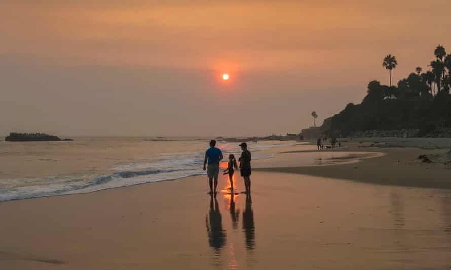 Beachgoers stand under a sky filled with ash and smoke at Laguna Beach on 11 September.