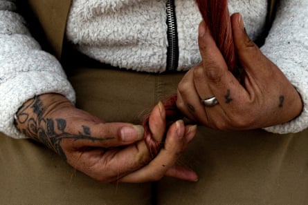 A woman’s tattooed hands twist her hair