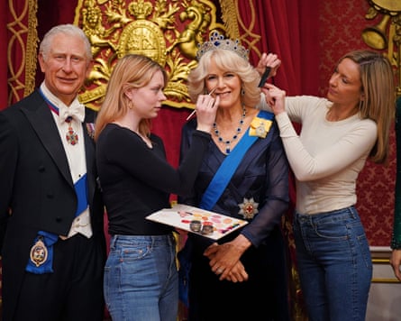 Waxworks of King Charles and Queen Camilla. Artists stand either side of the Camilla waxwork, making finishing touches