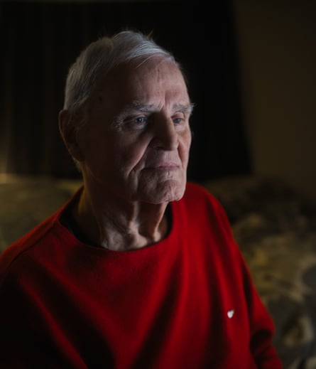 Portrait photograph of an older man with white hair and a wearing a red jumper