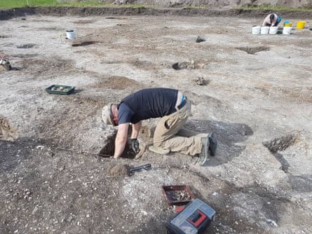 Person bending over looking onto ole in ground