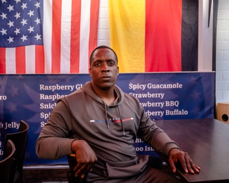 Leon Wilson sitting in front of a banner bearing the US and German flags.