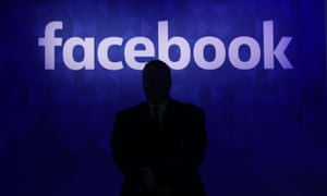 Silhouette of man in front of Facebook logo