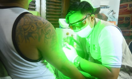 man wearing dark glasses holds bright green light up to client