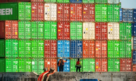 Two men in front of a high stack of colourful containers