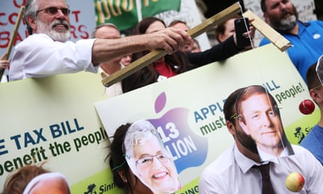 The Sinn Féin leader, Gerry Adams, hangs an apple in front of a man wearing an Enda Kenny mask during a demonstration supporting the European commission tax ruling.