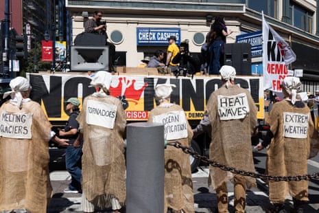 Demonstrators wear climate change-related signs at a “No Kings” protest on March 28, 2026 in San Francisco, California.
