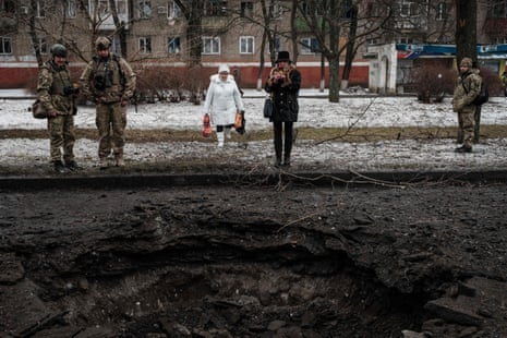 A woman takes a picture of a hole after a rocket strike, in Kramatorsk.