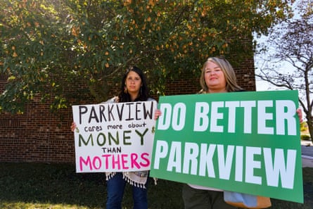 Two women hold signs during a protest against Parkview Health.