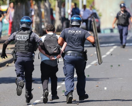 French police in riot gear detain a demonstrator during student protests in Saint-Pierre, on the French overseas island of La Reunion.