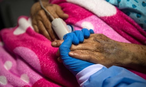 A health professional holds the hand of a COVID-19 patient