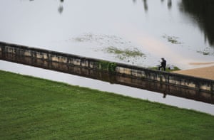 A man stands on his bike next to the flooded gardens of Chambord Castle.