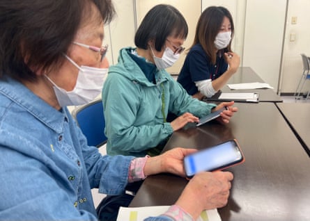 The smartphone learners, all wearing face masks, get to grips with their phones