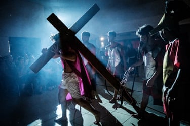 Image 9: A re-enactor dressed as Jesus carries the cross in low light