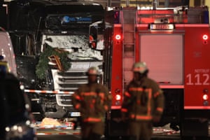Rescue workers walk near a damaged truck after it ploughed through a Christmas market in Berlin