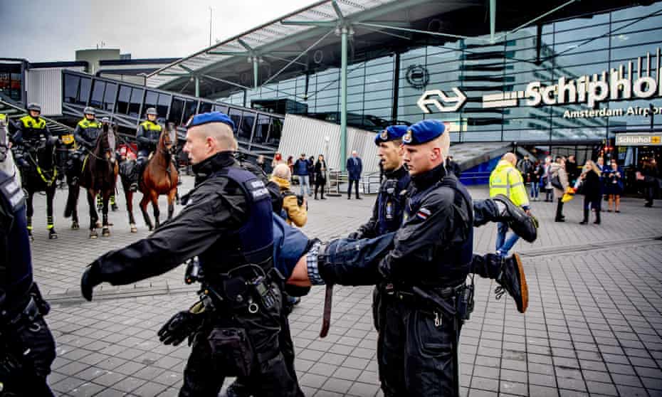 Royal military police remove a protester from the main hall of Schiphol airport.