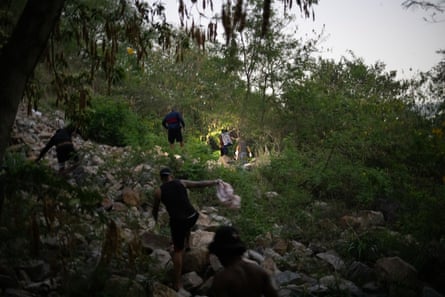 Men clamber up a hill among trees.