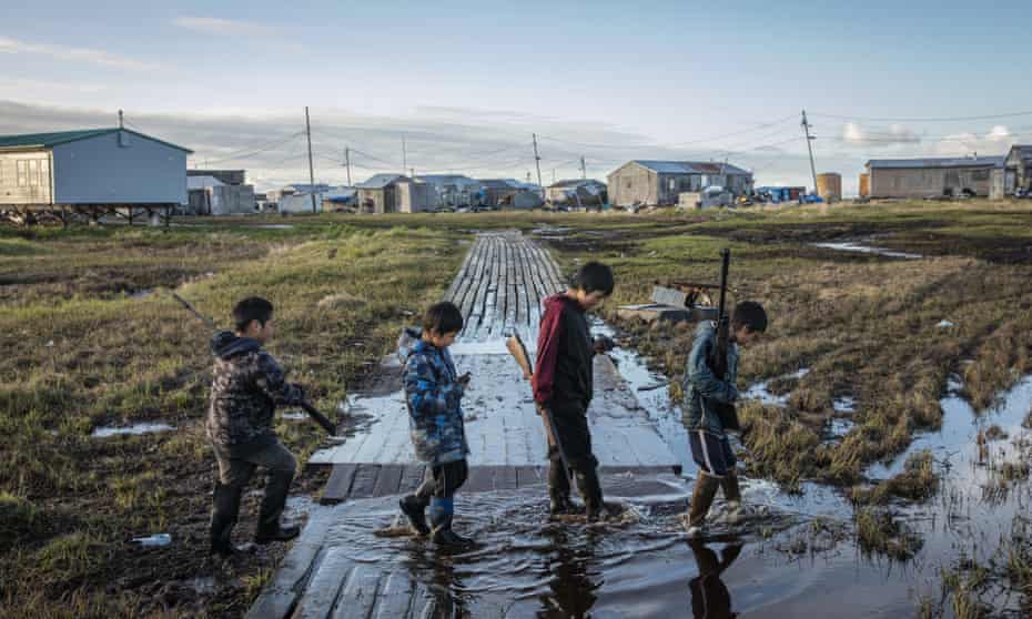 Boys cross a flooded walkway in Newtok, Alaska, a village which is sinking as a result of warming weather.