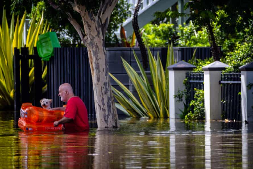 A man evacuates his dog as he wades through a flooded street in Paddington, Brisbane.