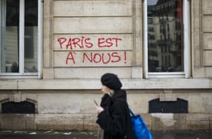 A woman walks past graffiti reading “Paris is ours”, near the Arc de Triomphe
