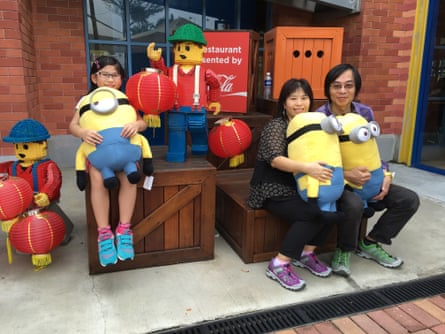Luna and her parents sitting outside a building holding large cuddly minion toys