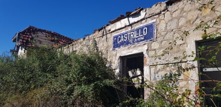 A crumbling stone building with tiles falling off its roof and vegetation obscuring its entrance