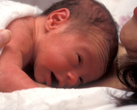 tiny premature baby lying on mother's chest in bed<br>AHM94X tiny premature baby lying on mother's chest in bed
