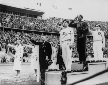 In this Aug. 11, 1936, file photo, America’s Jesse Owens, second from right, salutes during the presentation of his gold medal for the long jump, after defeating Nazi Germany’s Lutz Long, right, during the 1936 Summer Olympics in Berlin. Naoto Tajima of Japan, centre, placed third