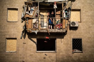 A man stands on a damaged balcony after Russian drone strikes killed or wounded several people