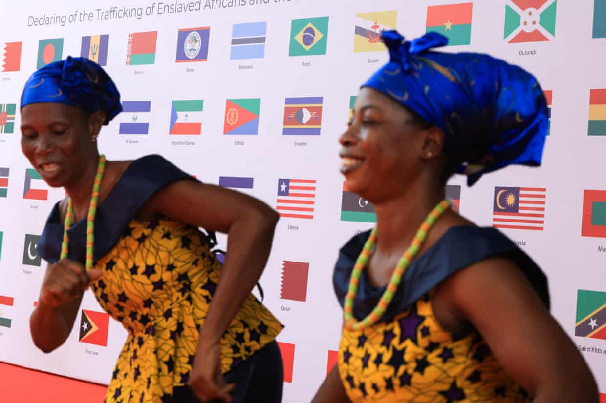 Dancers perform in front of a backdrop displaying country flags.