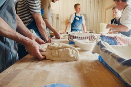 A group of people knead dough at a table at E5 Bakehouse.