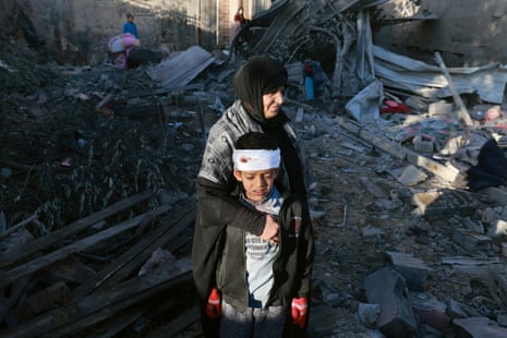 A Palestinian woman embraces a lightly injured boy as they check the rubble of a building after Israeli bombardment on 18 January in Rafah in the southern Gaza Strip, one of the areas that the Israeli military has repeatedly ordered the Gazan population to flee to for safety.