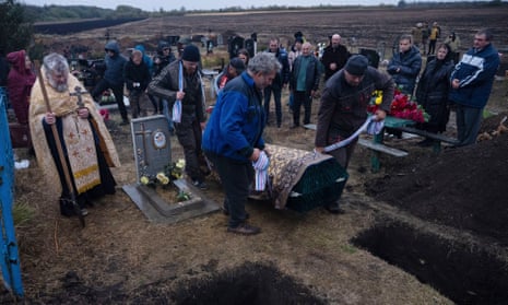 Men carry a coffin for burial during a funeral ceremony at a graveyard in the village of Hroza, near Kharkiv