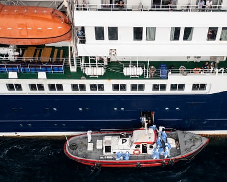 People in protective suits suits seen in a small boat alongside the MV Hondius.