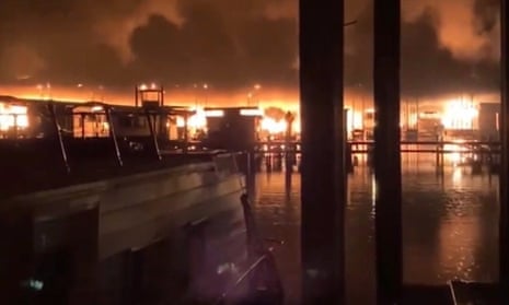 A fire burns on a dock where at least 35 vessels, many of them houseboats, were destroyed by fire.