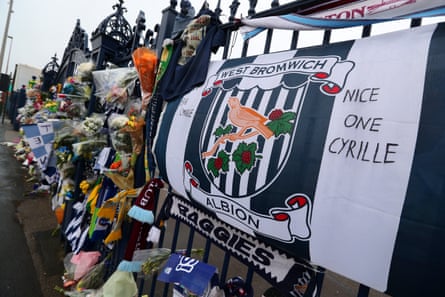Floral tributes along with shirts and scarves left by fans in memory of Cyrille Regis on the Jeff Astle gates at The Hawthorns.