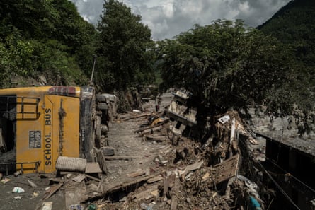 An overturned school bus lies in the mud