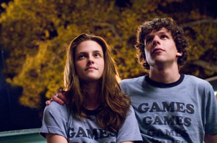 A girl with long dark hair and a young man with red curly hair, both wearing T-shirts with the words 'Games, Games, Games', staring up at the sky, with trees behind them