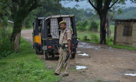 An Indian police officer stands guard near the site in the state of Assam where two men where lynched earlier in July