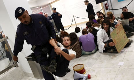 Portuguese police remove a climate change protester from a building where the economy minister, António Costa e Silva, was giving a speech.