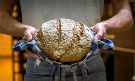 Baker holding a fresh loaf
