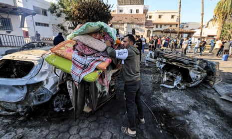 A man pushes a cart carrying salvaged mattresses, pillows, and sheets.