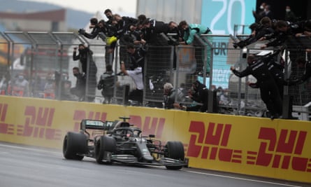 Lewis Hamilton crosses the finish line to win the Turkish Grand Prix as his team celebrate at trackside. Photograph: Tolga Bozoğlu/AP