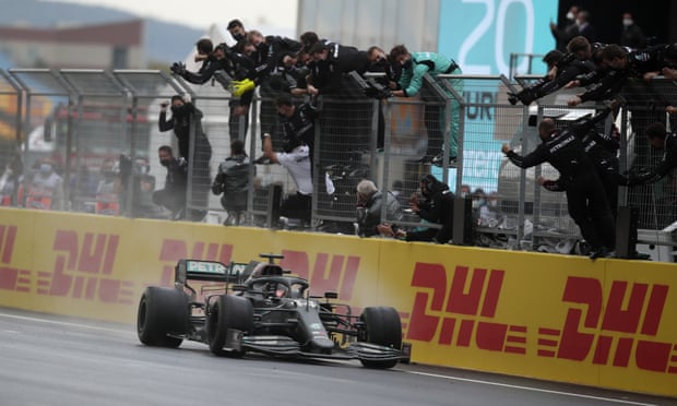 Lewis Hamilton crosses the finish line to win the Turkish Grand Prix as his team celebrate at trackside
